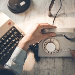 Image of vintage typewriter and hands on a vintage telephone